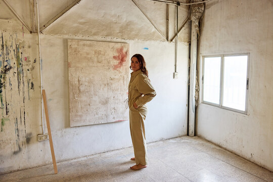 Young woman poses in minimalist art studio with creative vibe