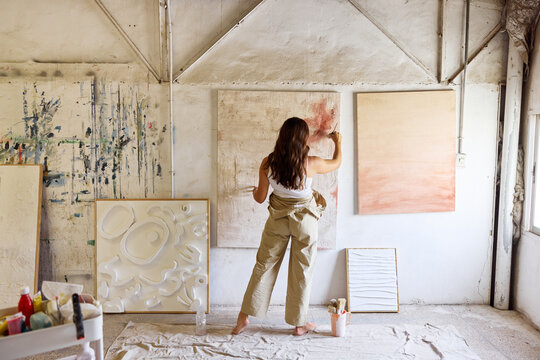 Artist creating abstract artwork in studio space during daytime