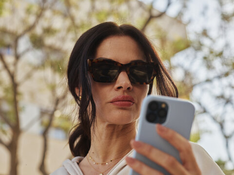 Woman Using Smartphone While Enjoying a Sunny Day Outdoors
