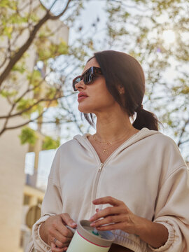 Young Woman Enjoying a Sunny Day in the City With tumbler