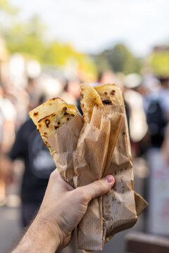 Man&rsquo;s hand holding lavash wraps at an outdoor food market