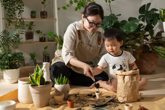 Mother and child planting together in a bright, plant-filled room