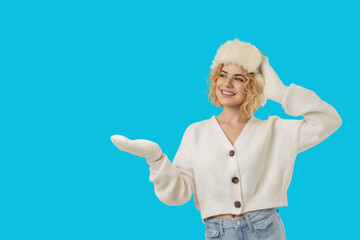 Woman wearing a cozy sweater and furry hat gesturing cheerfully