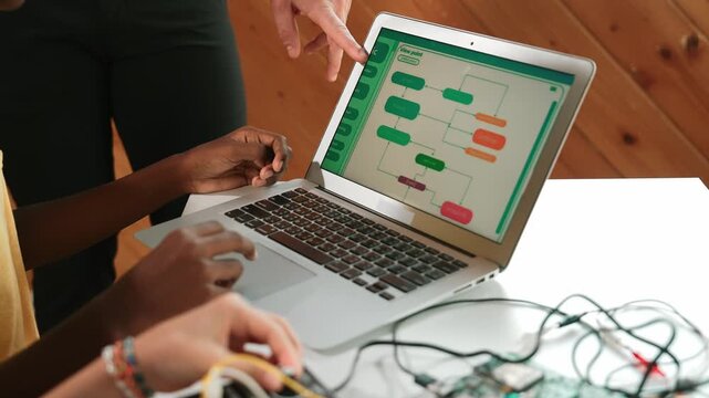 Top view of diverse children working together coding program. while caucasian teacher check and inspect system. Young children using electronic tool to fix motherboard at STEM class. Edification
