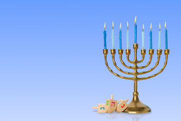 Menorah with lit blue candles beside colorful dreidels
