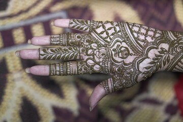 A traditional Bengali woman decorated mehendi on bride's hand during her wedding 