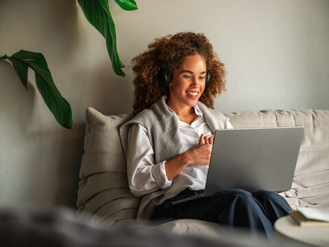 Casual Office Scene With Woman Wearing Headphones Working on Laptop
