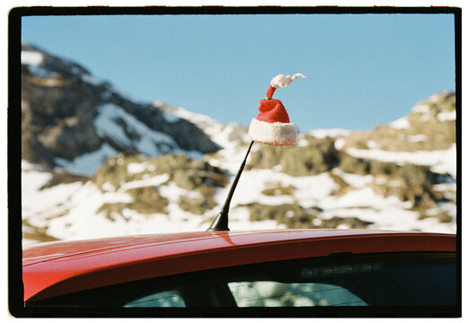 Small Santa hat on car antenna in snowy mountain landscape