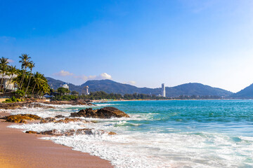 Tropical turquoise clear water waves rocks Patong Beach Phuket Thailand.