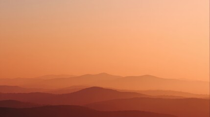 Distant mountain ranges in silhouette against a soft orange and yellow gradient sky mountains landscape