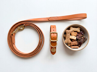 Premium leather dog leash, collar and treats neatly arranged on a clean white surface. High quality pet accessories with detailed texture, minimal modern layout