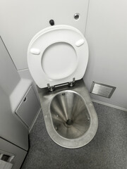 Public restroom in a commuter train car. A metal toilet, white walls