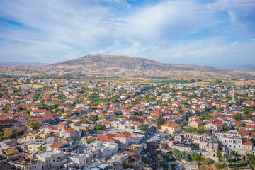 Obraz premium A vibrant aerial view of a town in Cappadocia, Turkey, featuring a picturesque cluster of red-roofed houses surrounded by greenery and narrow streets