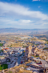 Obraz premium A stunning elevated view of Cappadocia, Turkey, featuring dramatic rock formations, fairy chimneys, and a charming village with traditional stone houses and a mosque minaret