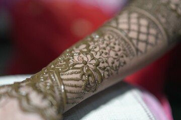 Bengali bridal mehendi design being applied on woman&rsquo;s hand close up