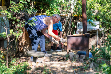 Grandfather teaching grandson to light outdoor stove, Grandfather and grandson preparing food on an outdoor stove in the backyard