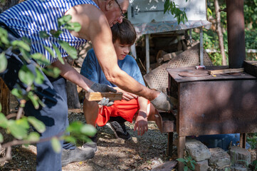 Grandfather teaching grandson to light outdoor stove, Grandfather and grandson preparing food on an outdoor stove in the backyard