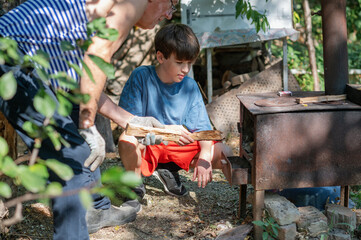 Grandfather teaching grandson to light outdoor stove, Grandfather and grandson preparing food on an outdoor stove in the backyard