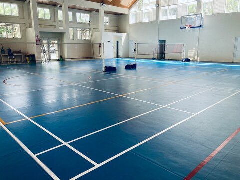 empty indoor sports court with badminton net and basketball hoop