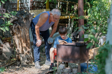 Grandfather teaching grandson to light outdoor stove, Grandfather and grandson preparing food on an outdoor stove in the backyard