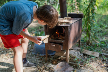 Grandfather teaching grandson to light outdoor stove, Grandfather and grandson preparing food on an outdoor stove in the backyard
