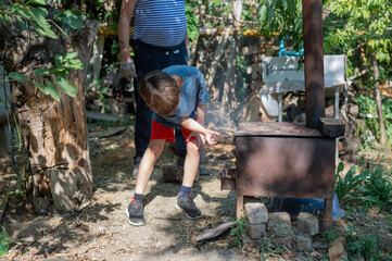 Grandfather teaching grandson to light outdoor stove, Grandfather and grandson preparing food on an outdoor stove in the backyard