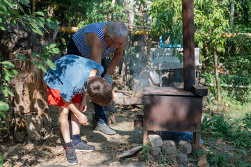 Grandfather teaching grandson to light outdoor stove, Grandfather and grandson preparing food on an outdoor stove in the backyard