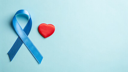 A blue ribbon lays beside a red heart on a light blue background, representing support and awareness