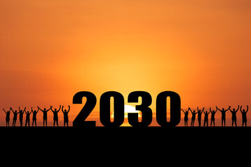 Silhouetted figures standing against a vibrant sunset sky celebrating 2030 year. They are reaching towards the future with hopeful energy.  © Stock4u2024 