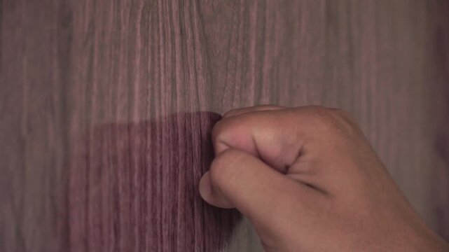 Detailed video of fingers knocking on a wooden surface, illustrating a person requesting entry or attention.