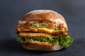 Spicy Mexican Chicken Burger with Guacamole, Fresh Salsa, and Melted Cheese on Dark Background - Gourmet Fast Food Sandwich Concept