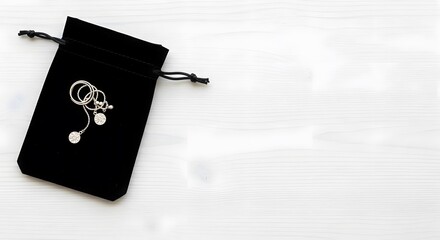 Elegant earrings peeking out of a black velvet pouch on white wood
