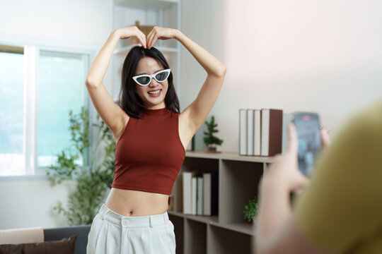 Social Media Fun. Young woman making a heart shape while posing for a video.