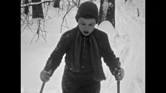 Retro archive, boy child on skis slides from snowy slope in winter forest. Fun childhood in snow outdoor. Skier skiing in cold nature. Kid leisure in vacation activity. Vintage film. Old archival