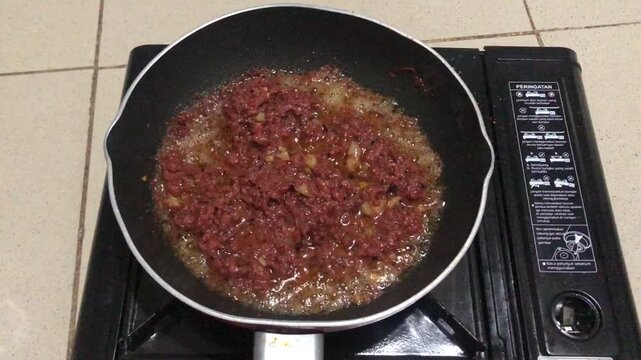 Cooking corned beef hash in a frying pan on a portable gas stove