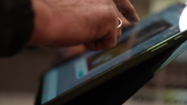 Modern mechanic using digital tablet interface for vehicle diagnostics in workshop environment with close-up focus on hands operating touchscreen