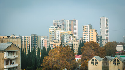 Autumn cityscape of Tbilisi under heavy smog, showing a contrast between old and modern buildings with hazy skyline and muted colors, evoking urban melancholy and environmental concern