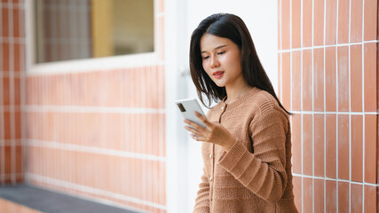 Beautiful Asian woman checking social media chatting on smartphone lifestyle outdoor