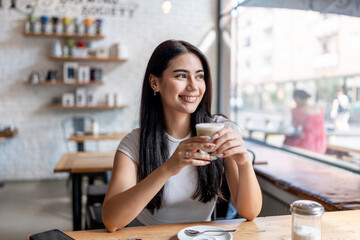 Mixed race woman drinking a cup of coffee at a table in cafe restaurant. 