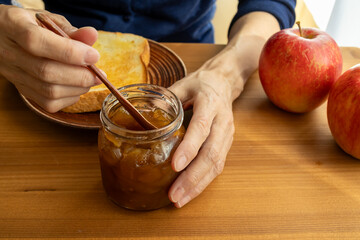 手手作りのりんごジャムをパンに塗る女性