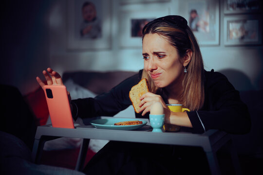 Anxious Woman Checking her Phone While Having Breakfast in Bed. Lady doom eating while scrolling not focusing enough on her meal
