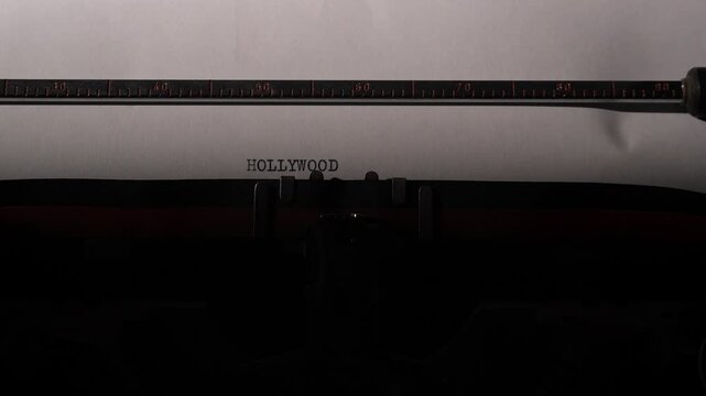 Vintage typewriter showing the word hollywood typed on a sheet of paper, symbolizing screenwriting, film industry, entertainment, storytelling, and the golden age of cinema