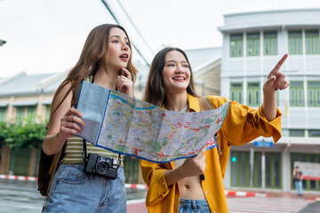 Two Asian women search direction on the map while traveling in the city.