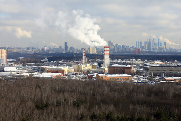 Fototapeta premium Industrial plant with smoking chimney and city skyline in background