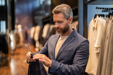 Shop manager show elegant suit. Man wearing classic tailored suit while shopping in boutique....