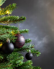 Black Christmas Ornament on Evergreen Tree with Festive Lights and Dark Bokeh Background