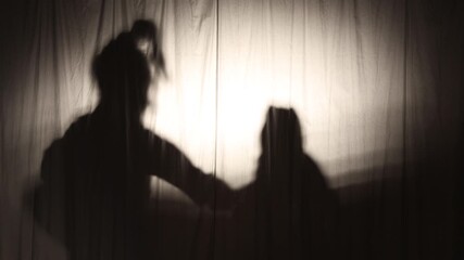 Shadowy figures of two performers in dramatic poses behind a curtain, creating a mysterious theatrical atmosphere with copy space