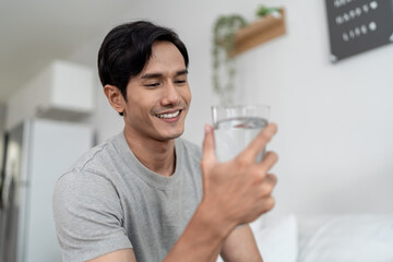 Asian handsome young man drinking a glass of water in the morning. 
