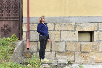 Woman looking up outdoors by stone wall