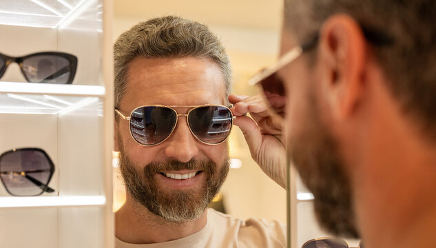 Fashionable man. Trendy sunglasses accessories for men. Eyewear collection. Fashion look with sunglasses. Man choosing sunglasses in shop. Sunglasses model in fashion store. Browsing eyewear racks